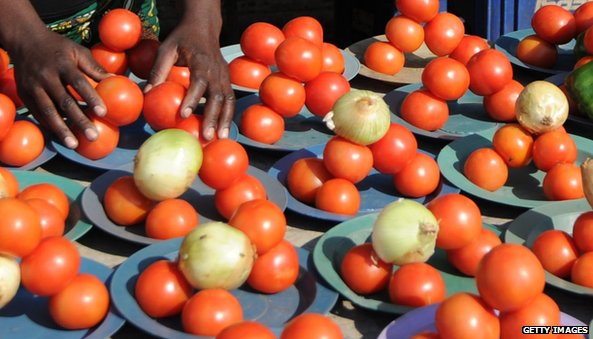 African woman holds fruit on her stall